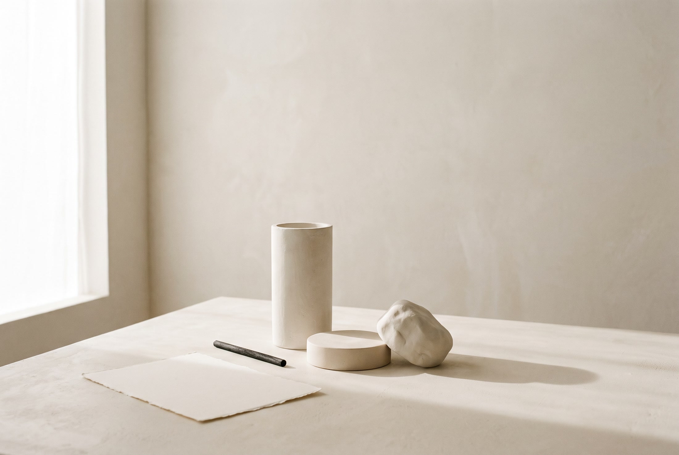 A designer's atelier worktable with brand sketches, paper samples, and drafting tools in warm light.